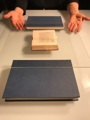 Balancing a tightly bound book under plexi, using (non-collection) books as a support to prevent pressure on the spine, and foamcore underneath the front and back covers for extra protection.